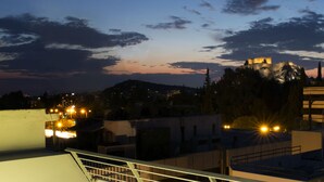Terraço no telhado com grama sintética, uma cadeira branca e um corrimão.