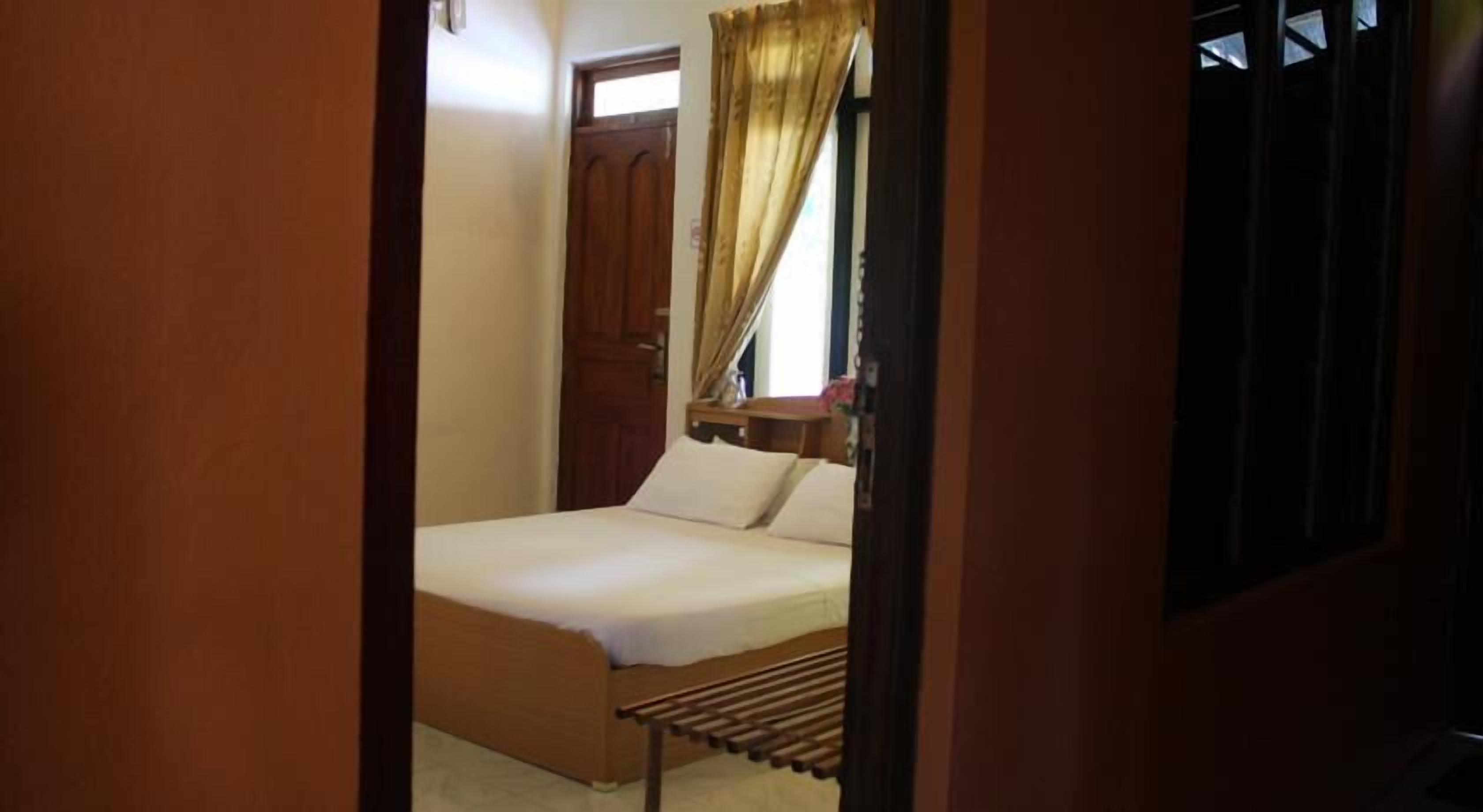 Un letto singolo con struttura in legno e testiera, un comodino e una finestra con tende.