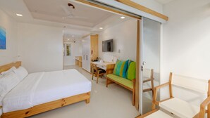 A modern bedroom with a wooden bed, a desk, a chair, and a sofa. - Luau Beach Inn (Fulidhoo)