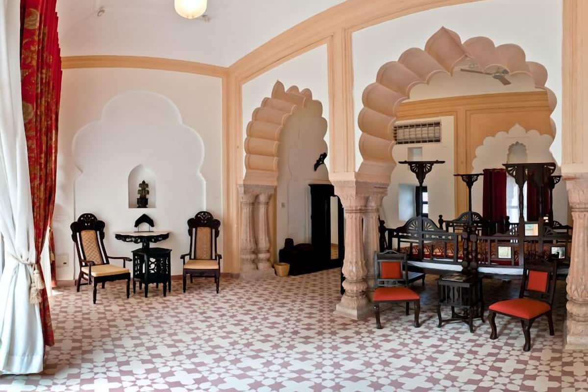 A room with a patterned floor, arched doorways, and traditional furniture.