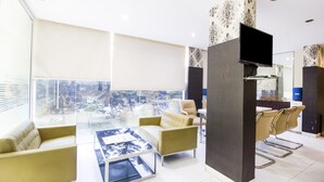 A modern living room with a sofa, armchairs, a coffee table, and a TV. - FabHotel M Hotel Hitech City (Hyderabad)