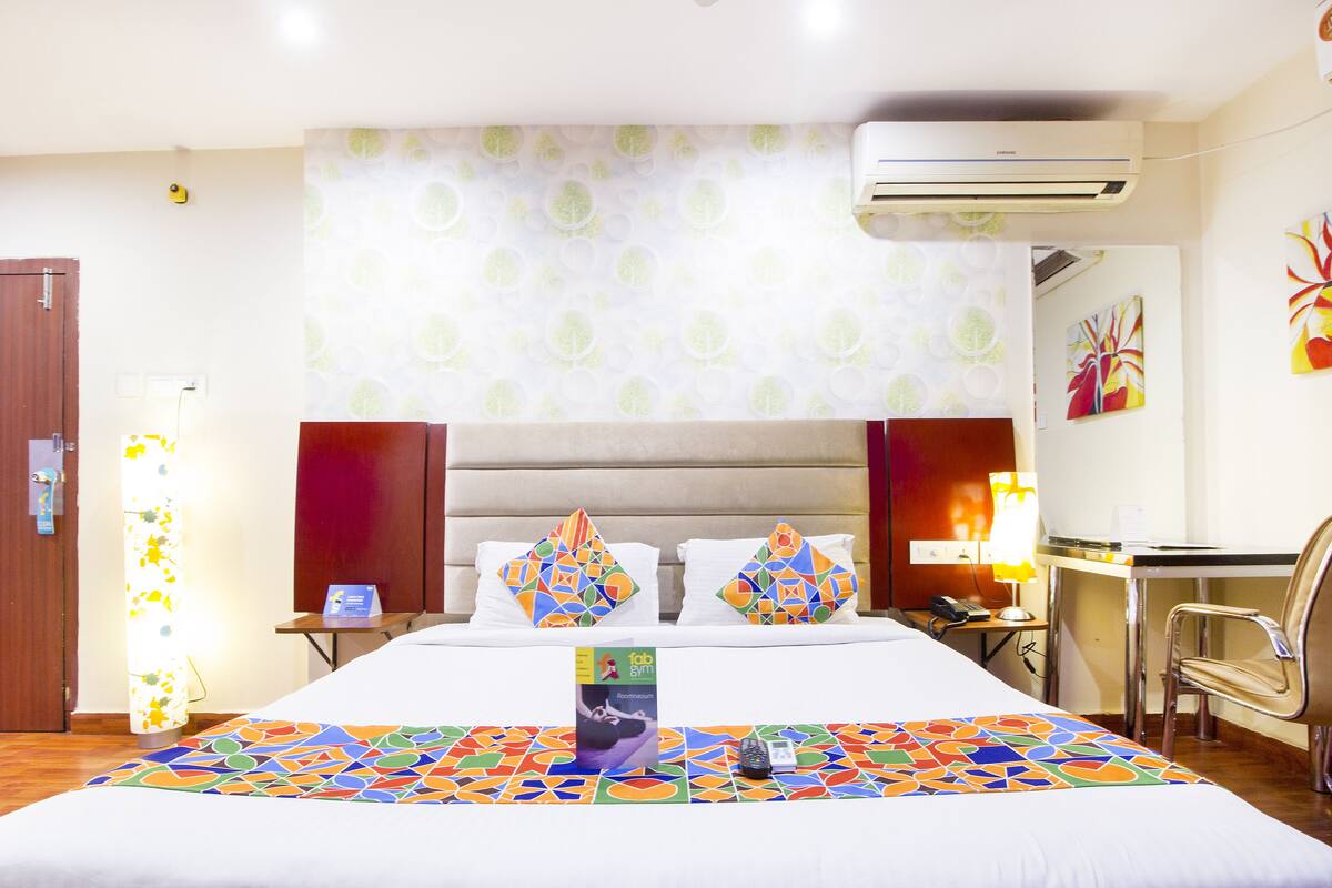 Ein Hotelzimmer mit Bett, Schreibtisch, Stuhl, Klimaanlage und einer Wand mit strukturierten Tapeten.