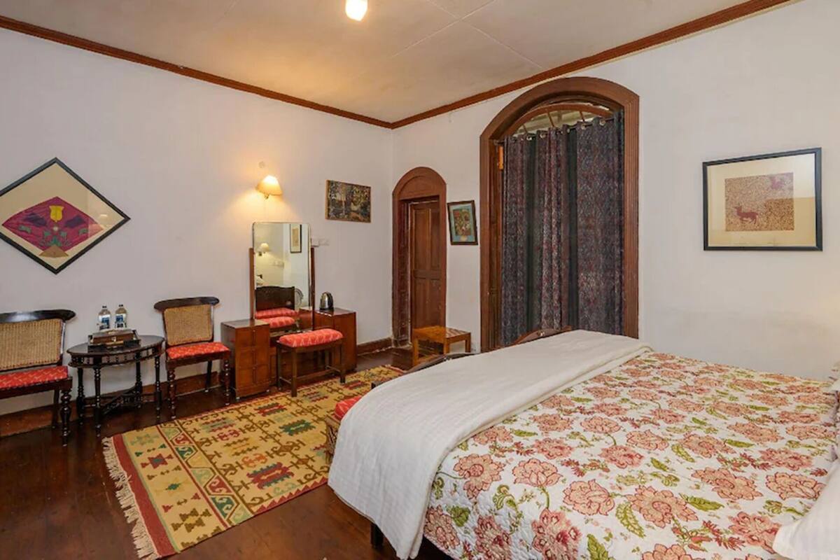 Un dormitorio con cama, escritorio, silla, espejo y puerta.