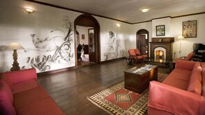 A spacious living room with a fireplace, red sofas, a coffee table, and a patterned rug.
