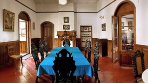Un comedor con una larga mesa, sillas ornamentadas y una araña.