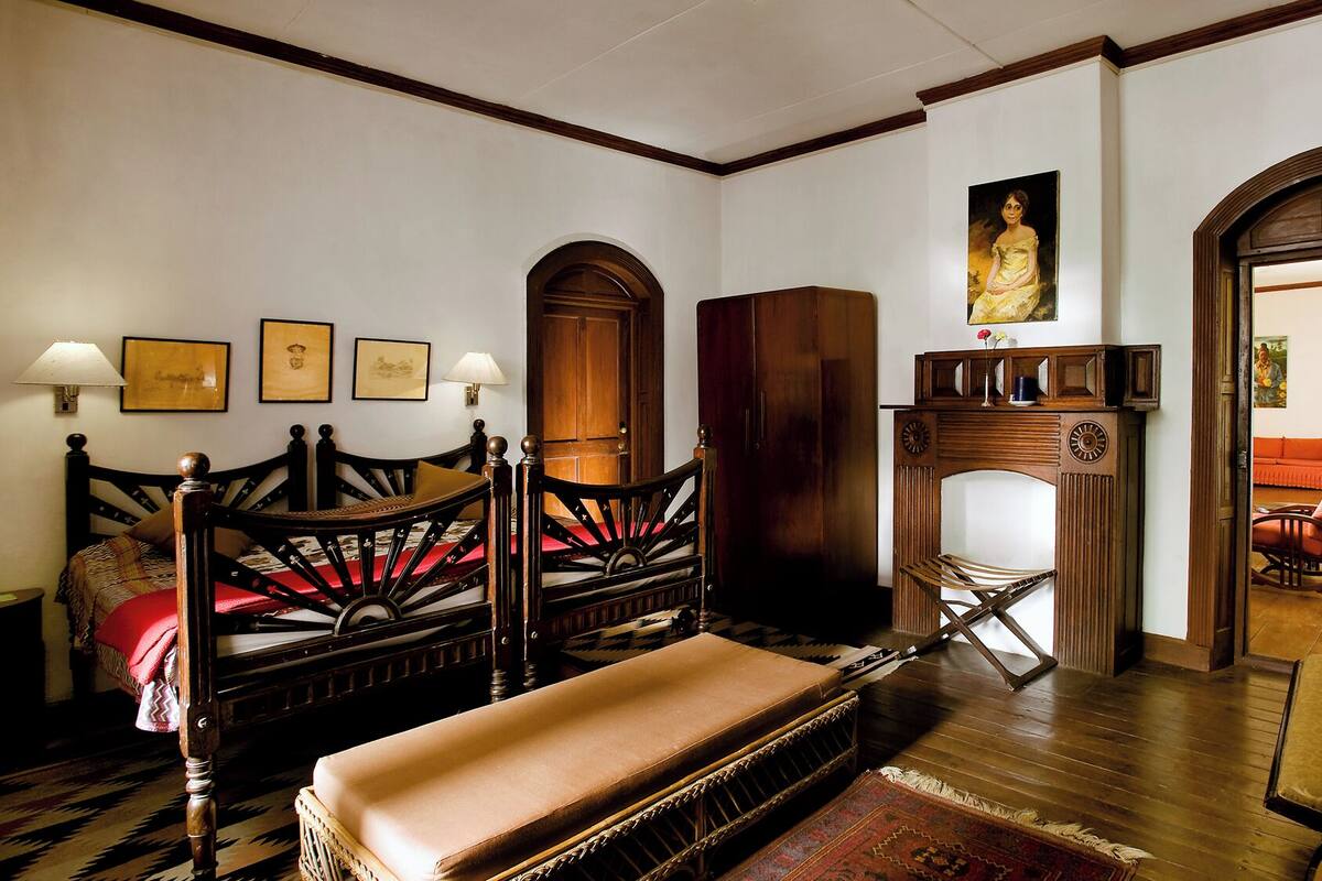 Una habitación tradicional con una cama de madera, una silla de madera, una mesita y una chimenea.