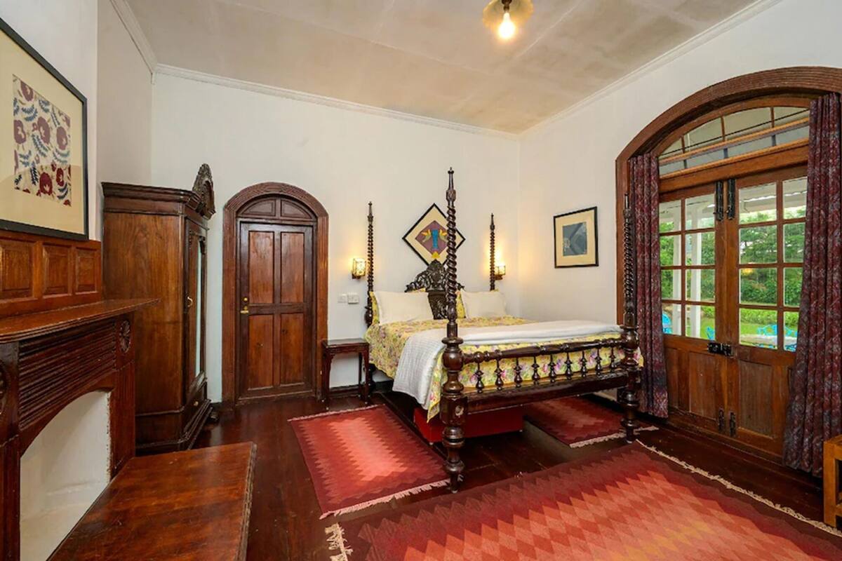 Un dormitorio tradicional con cama de dos plazas, muebles de madera y un ventanal con vistas.