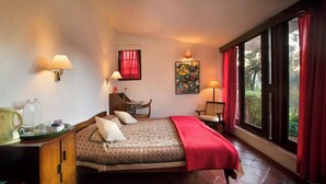 A bedroom with a bed, a desk, a chair, and a window with curtains.