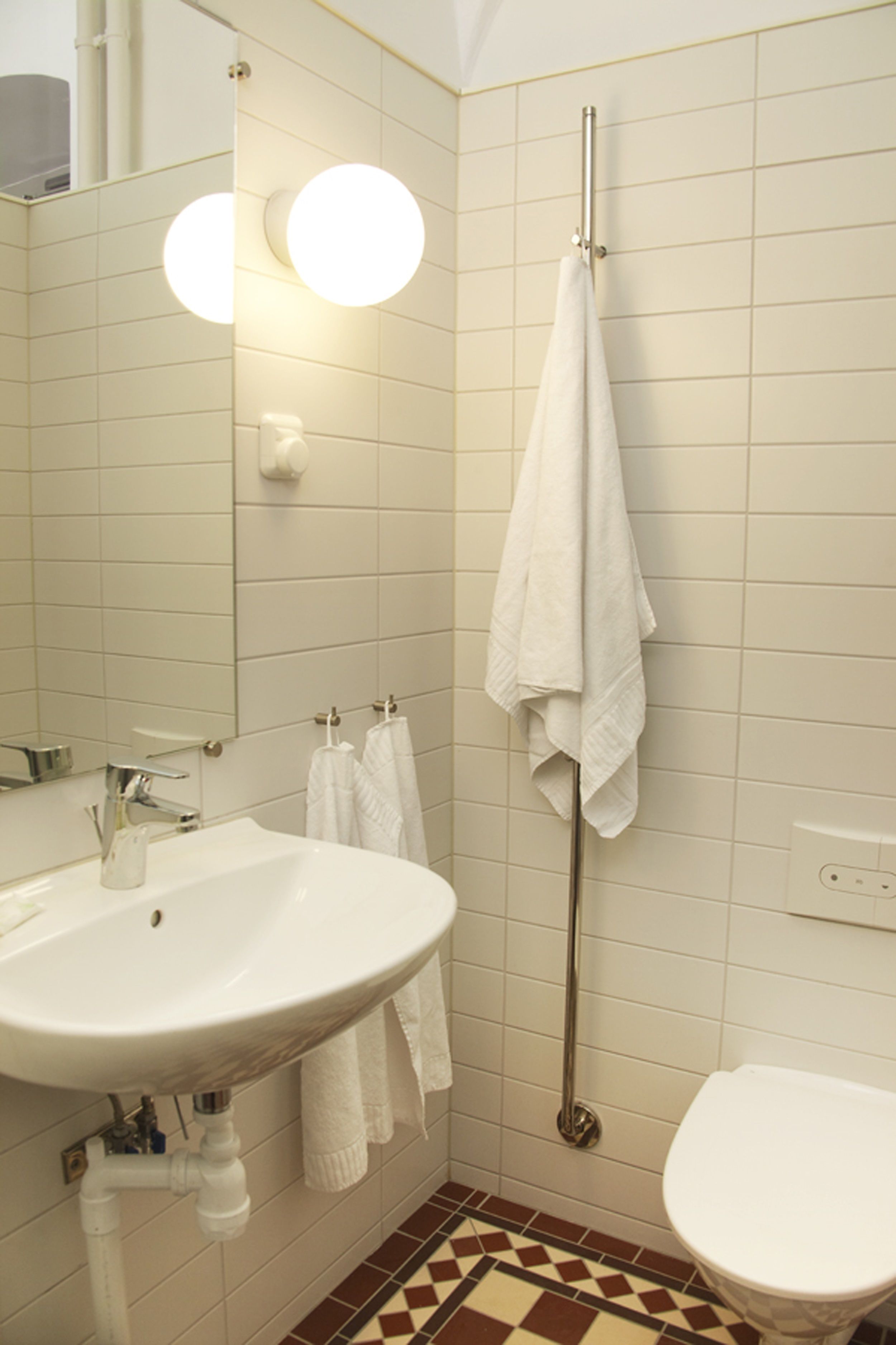 Ein Badezimmer mit Waschbecken, Spiegel, Handtuchhalter und Toilette.