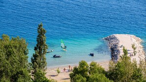 A beach with clear blue water, a sandy shore, and a few people. - Hotel Plaza Duce (Dugi Rat)