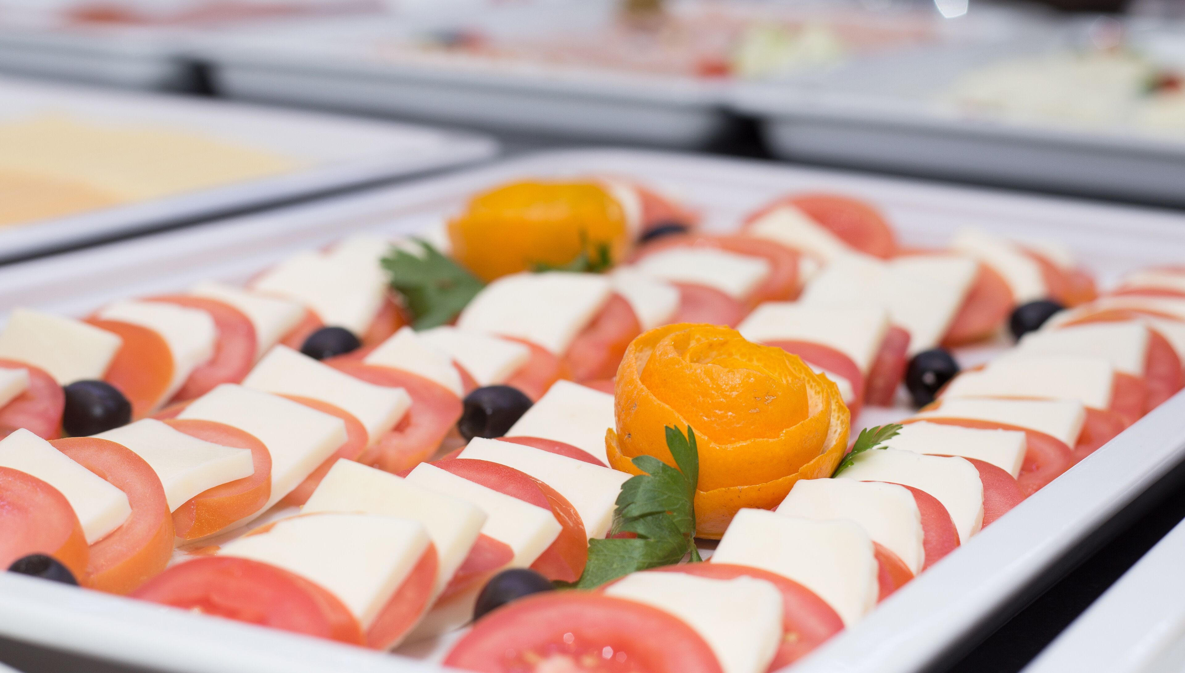 A buffet with various food items including sliced tomatoes, cheese, and oranges.