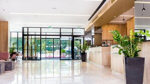 A modern hotel lobby with a reception desk, seating area, and large glass doors leading to the outdoors. - Hotel Plaza Duce (Dugi Rat)