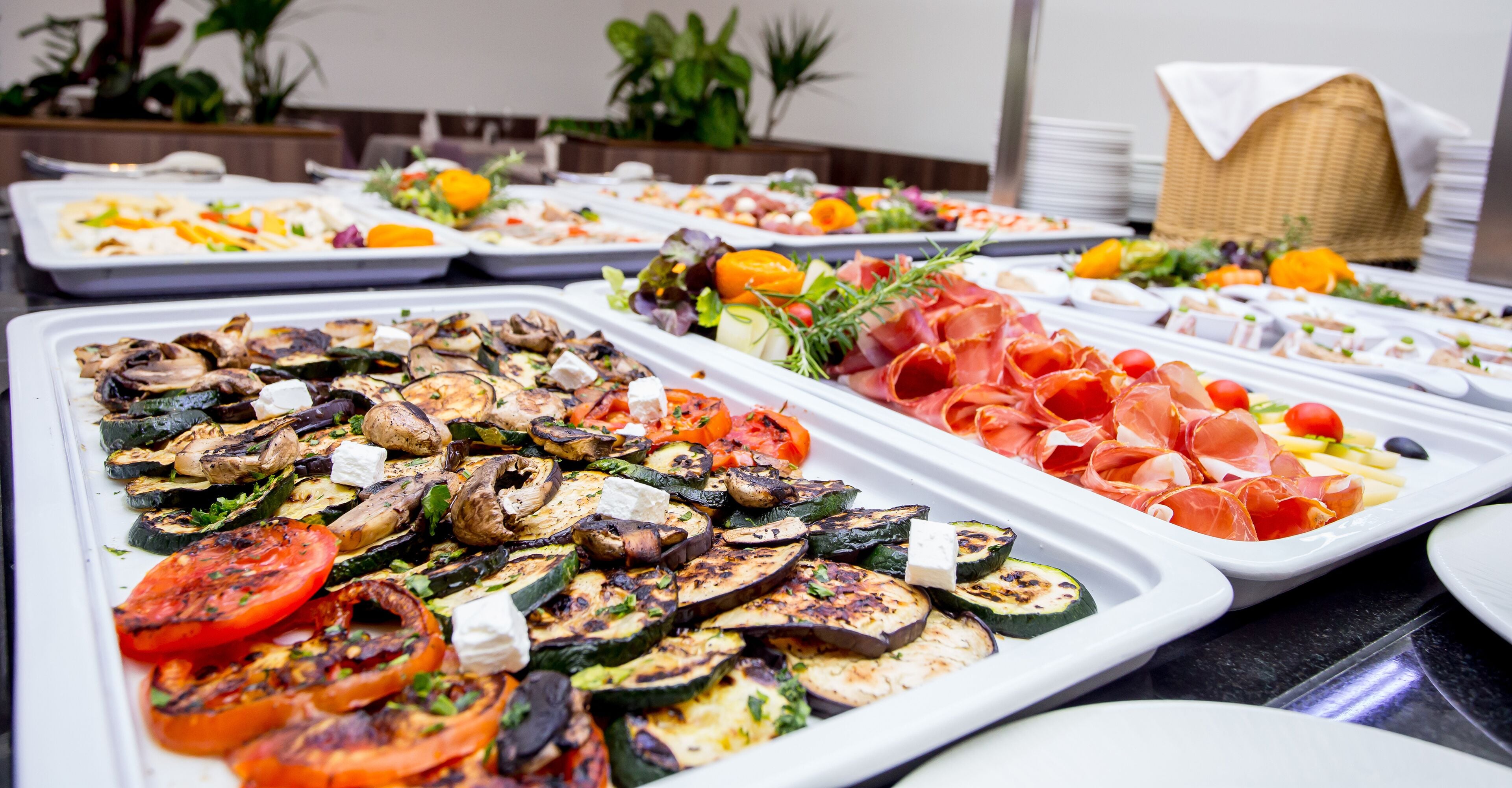 Un buffet proposant divers plats, notamment des légumes et des viandes grillés.