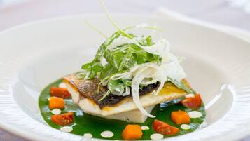 Un plato con pescado, verduras de hoja y vegetales.