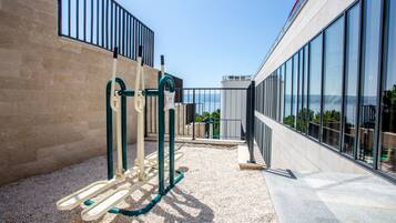 Un parque infantil con equipo de ejercicio, un muro de ladrillo y un edificio con ventanas grandes.