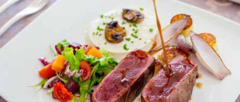 Un plato de comida con ensalada, una porción de queso y dos trozos de carne.