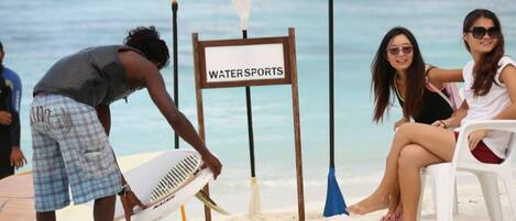 A beach scene with a sign labeled "WATER SPORTS" and a surfboard.