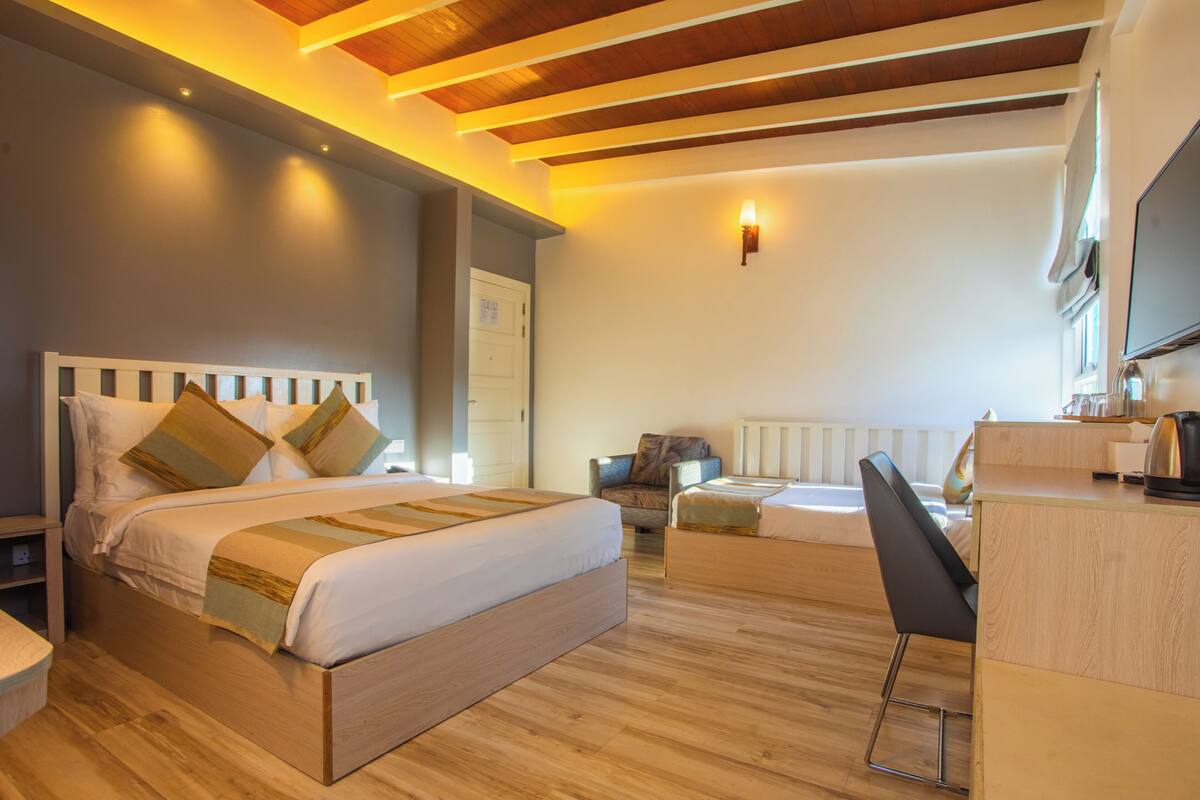 A hotel room with a bed, a desk, a chair, and a TV.