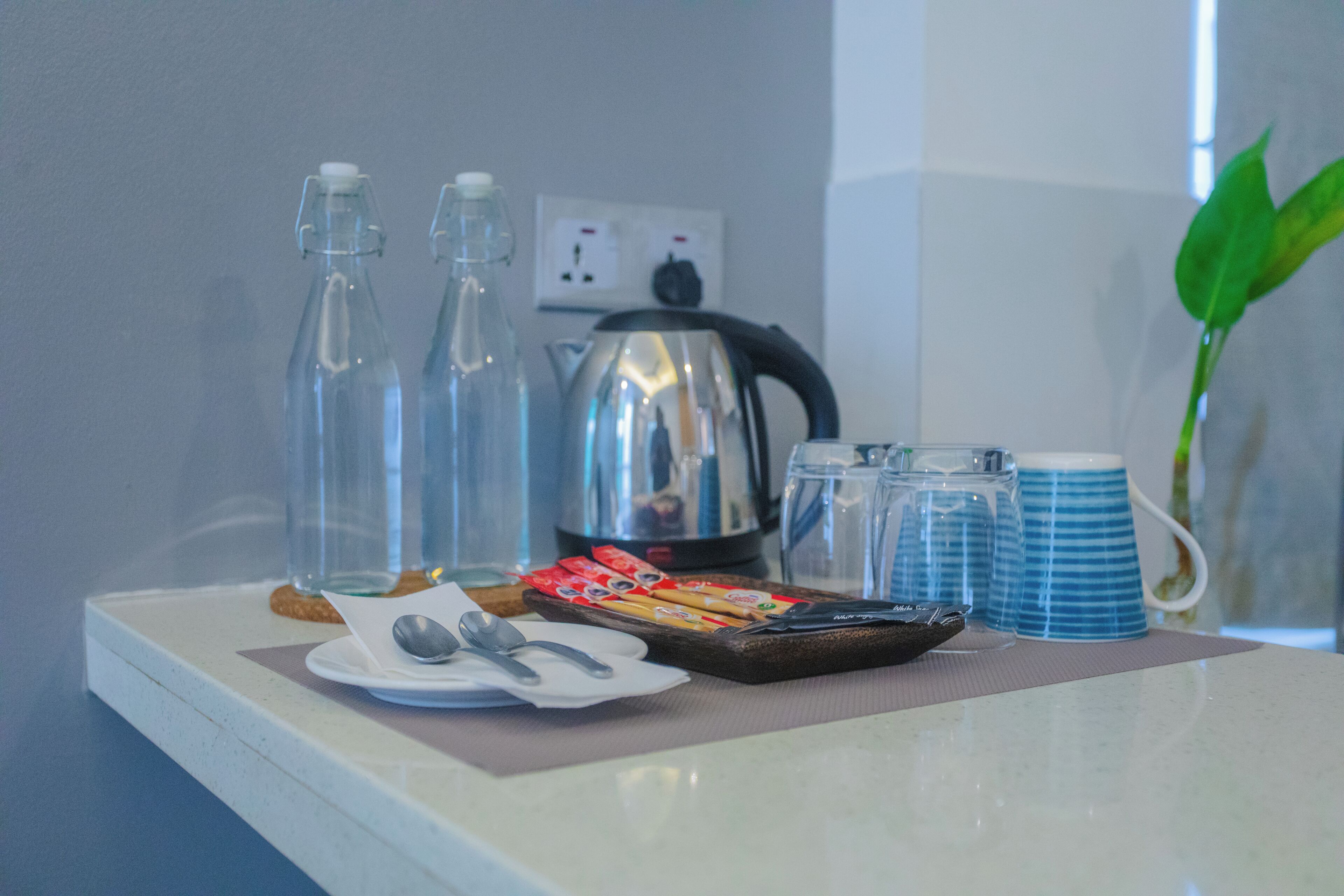 Een ontbijt opstelling met een waterkoker, kopjes en toevoegingen op een tafel.