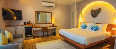 A modern bedroom with a bed, desk, and seating area, featuring a ceiling fan, air conditioning, and a heart-shaped wall decoration.