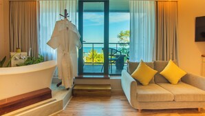 A modern hotel room with a bathtub, a sofa with yellow cushions, and a balcony with a view. - Coconut Tree Hulhuvilla Beach (Hulhumalé)