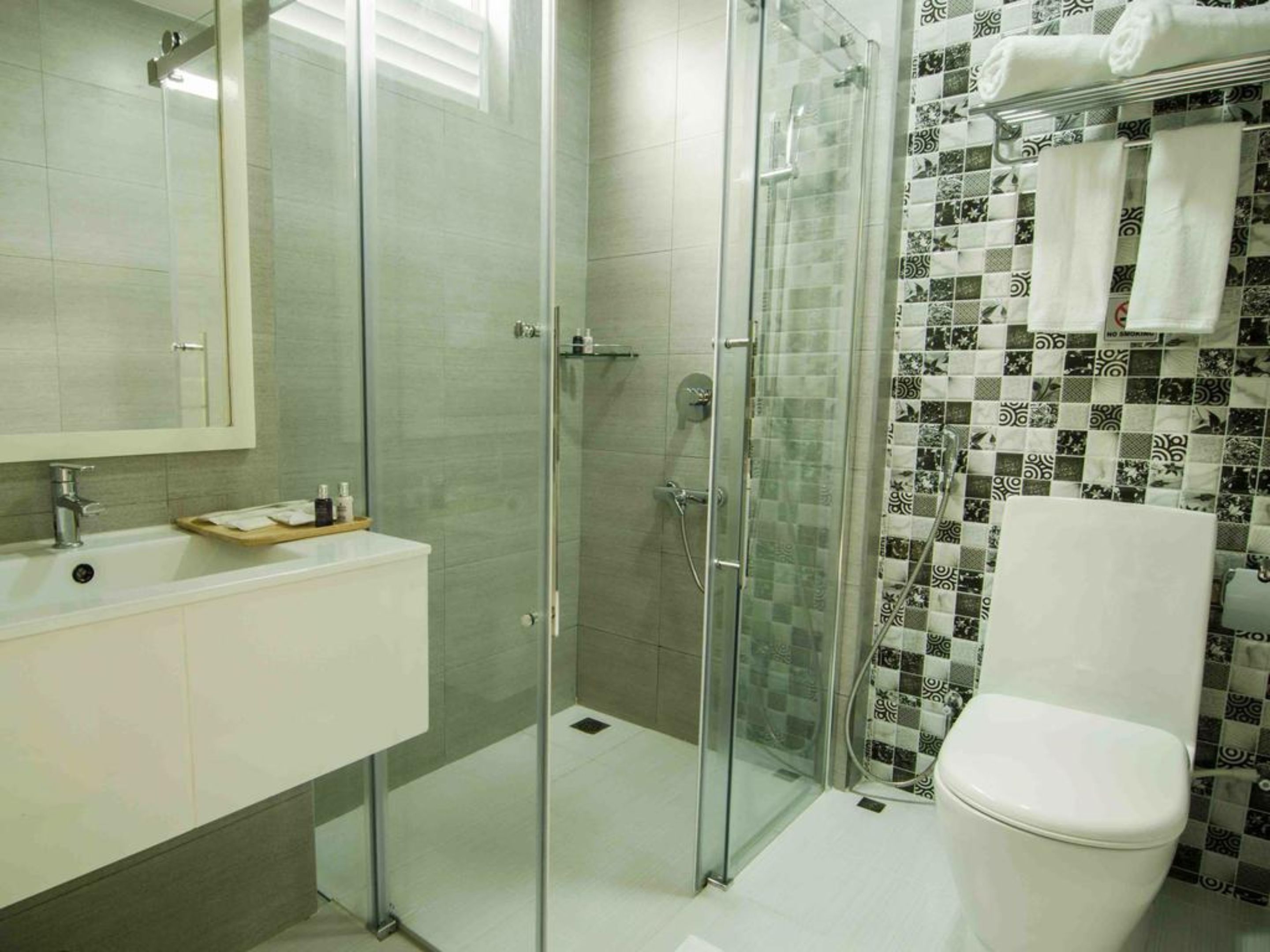 A bathroom with a glass-enclosed shower, a white sink, and a toilet.