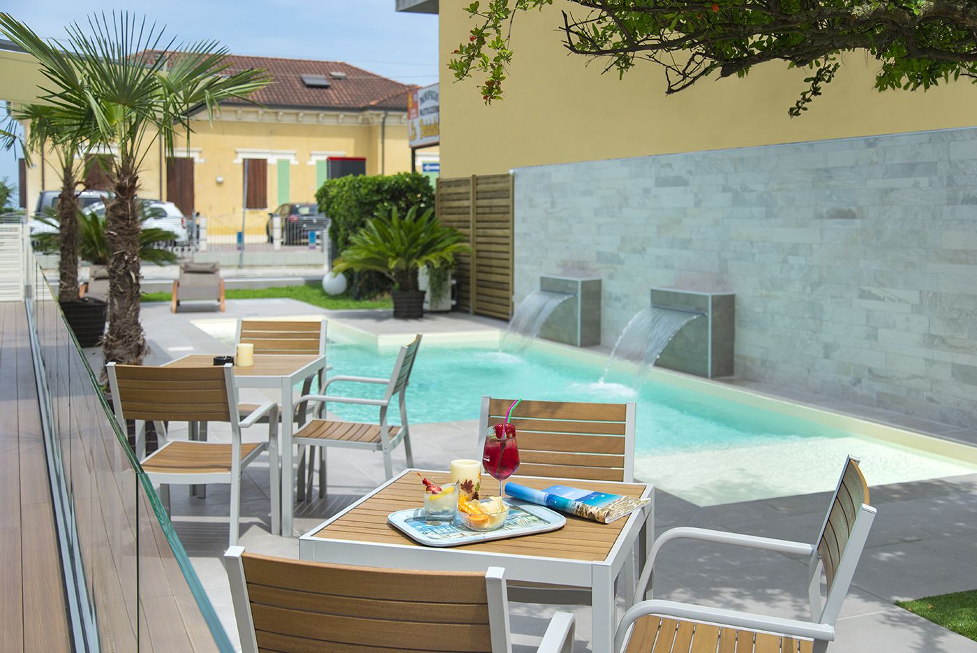 An outdoor pool area with lounge chairs and a table set with a drink and snacks.