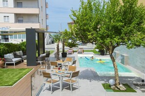 Un espace piscine aménagé sur le toit, avec des chaises longues et une vue sur le bâtiment de l’hôtel.
