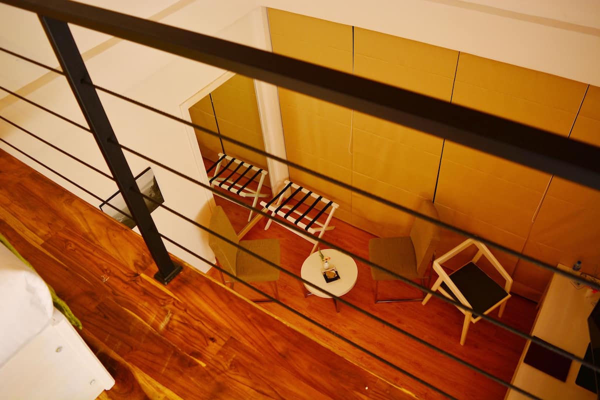 Una habitación con piso de madera, una mesa redonda blanca con un jarrón pequeño y dos sillas.