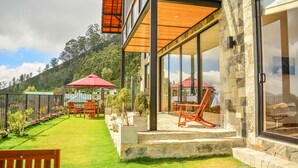 Une maison moderne avec une façade en pierre, de grandes fenêtres en verre et une pelouse bien entretenue.