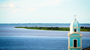 A coastal view with a church tower and a calm sea. - Barao Center Hotel (Santarém)