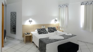 A hotel room with a bed, bedside tables, a TV, and a window with curtains. - Barao Center Hotel (Santarém)