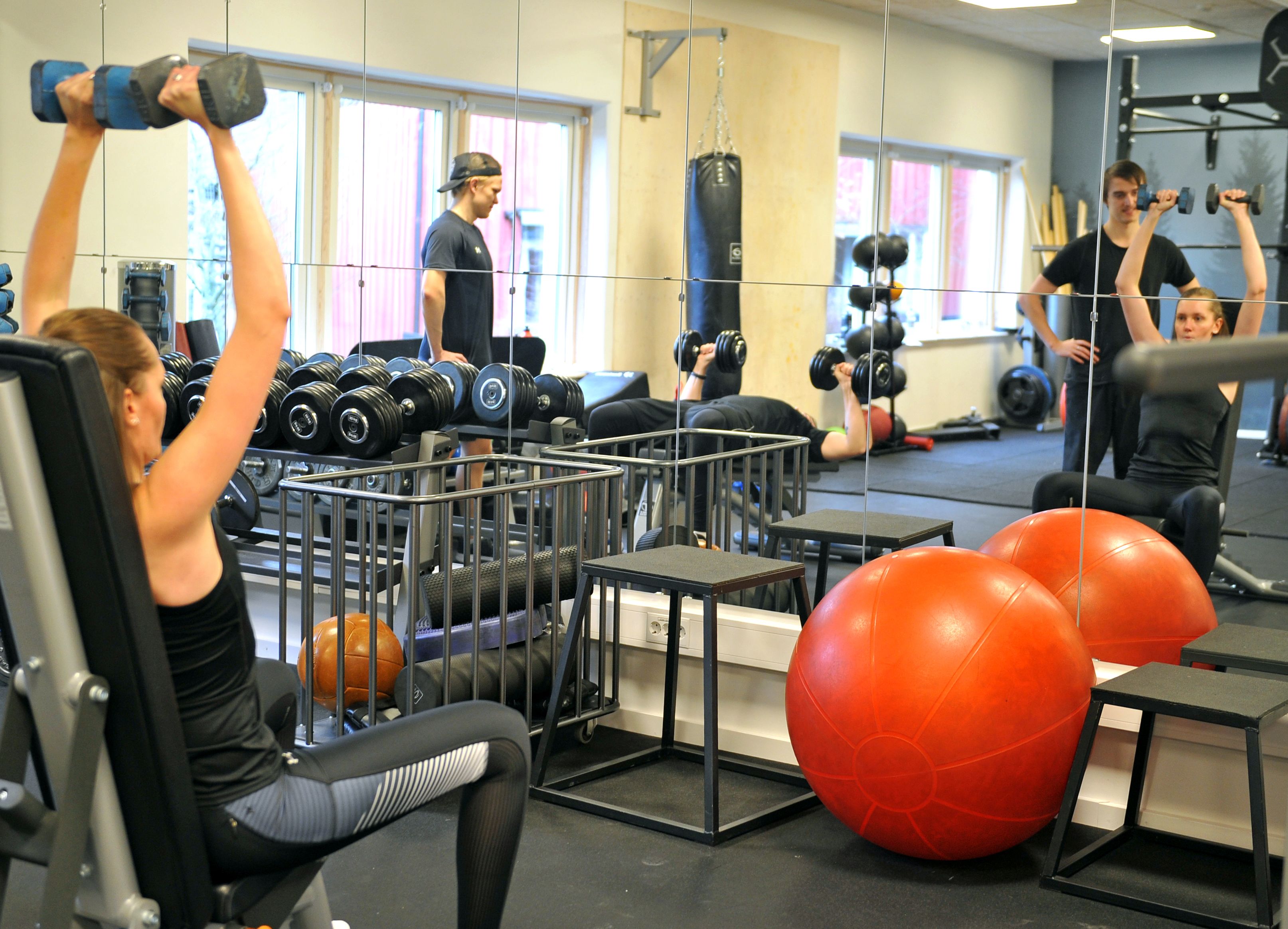 Un gimnasio con equipo de ejercicio, incluyendo mancuernas, balones medicinales y un saco de boxeo.