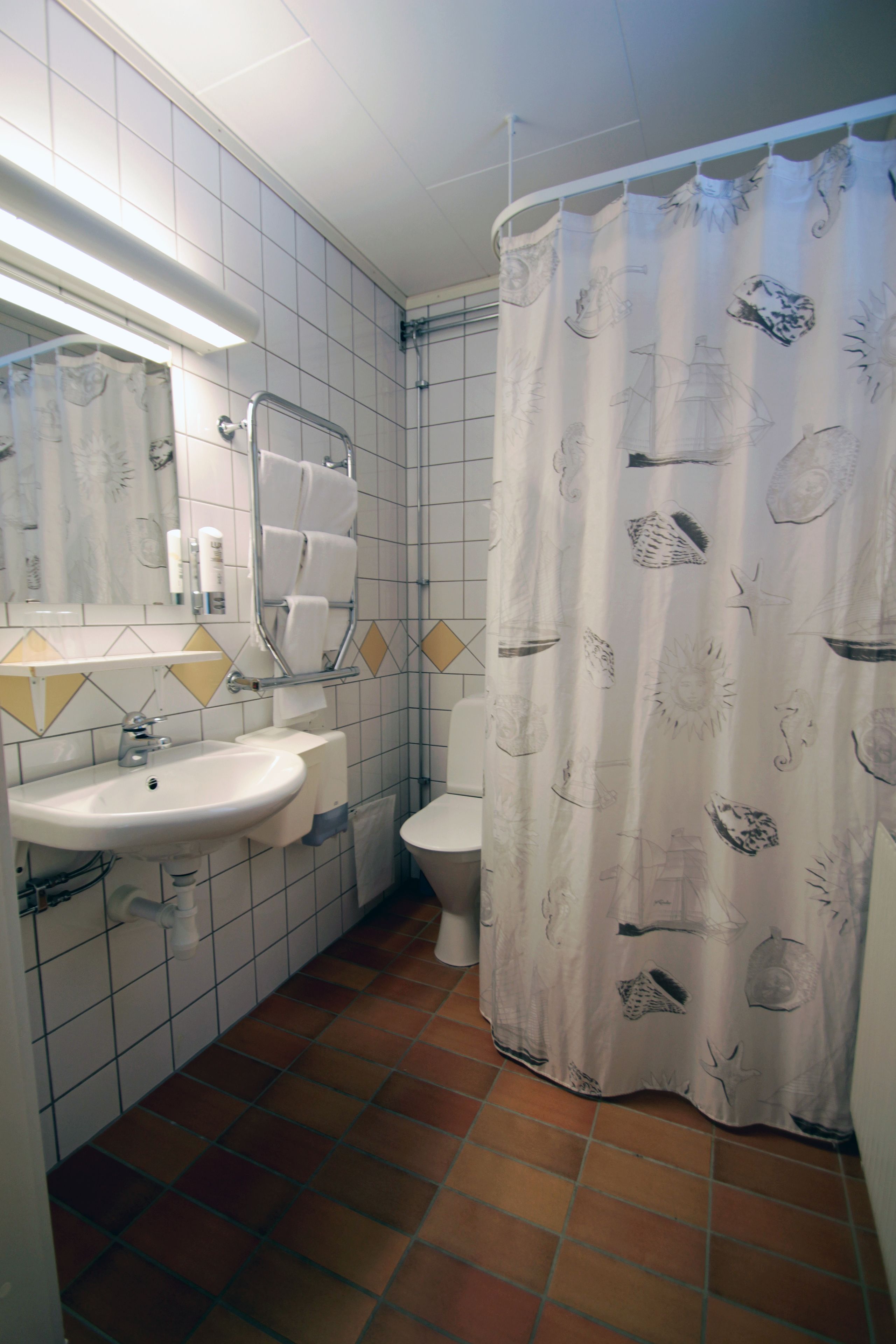 A bathroom with a sink, toilet, and shower curtain.