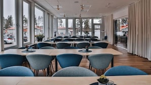 A modern conference room with large windows, blue chairs, and wooden tables. - Ädelfors Hotell och Konferens (Holsbybrunn)