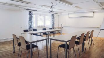Et mødelokale med et langt bord, stole, en projektor og en hvidtavle.