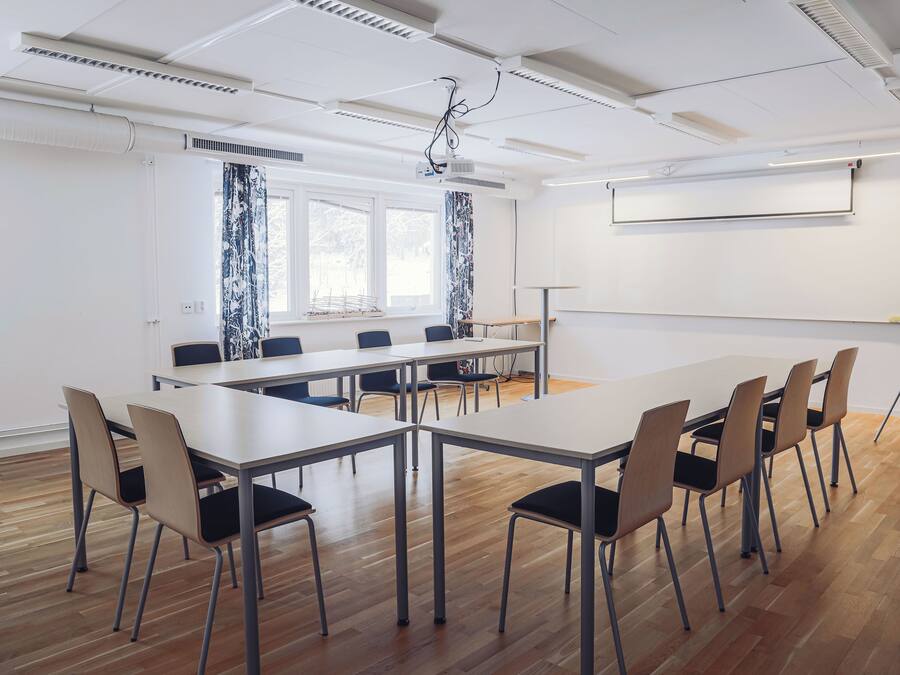 Et mødelokale med et langt bord, stole, en projektor og en hvidtavle.