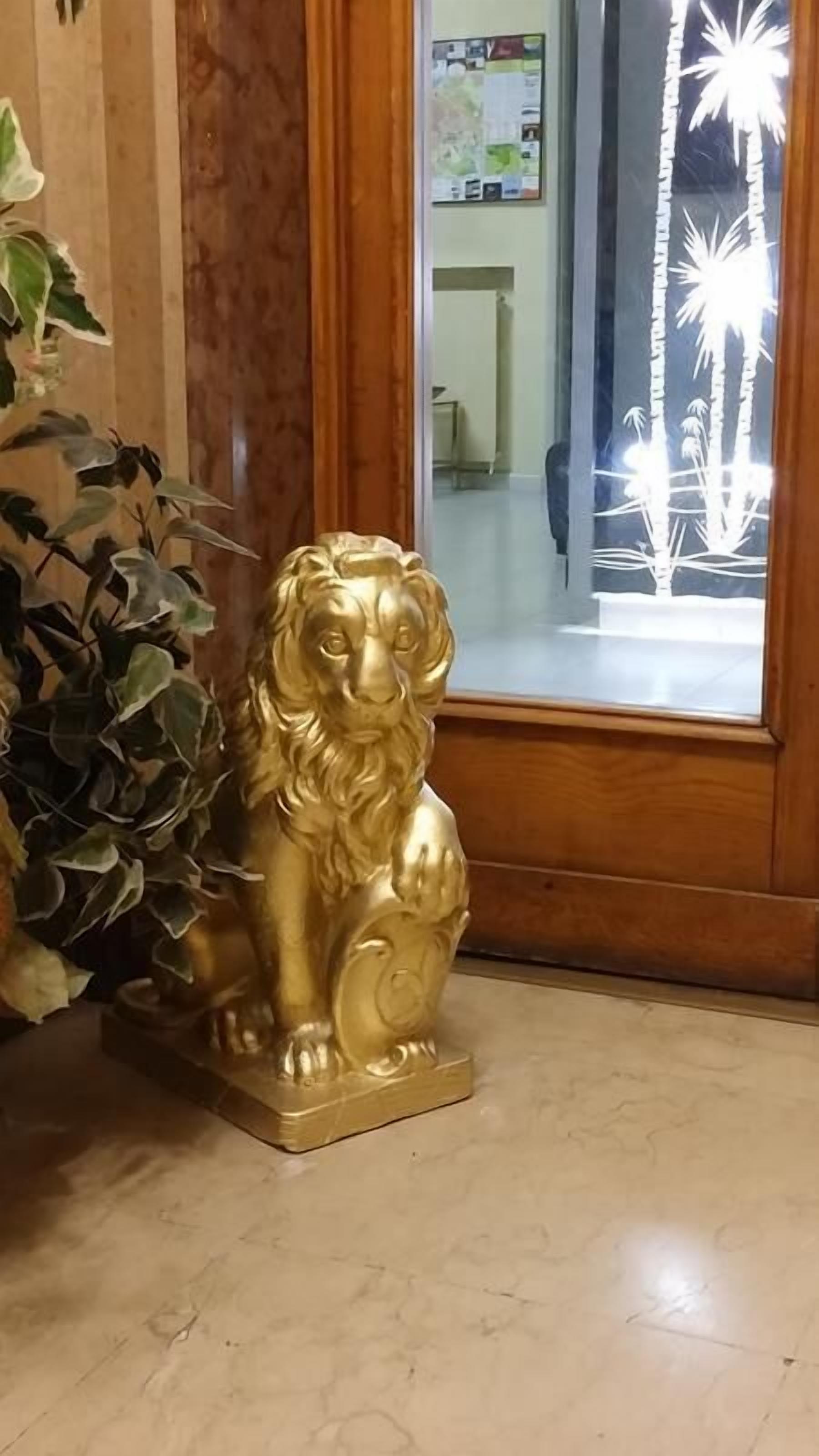 A golden lion statue on a tiled floor near a wooden door with a glass panel.