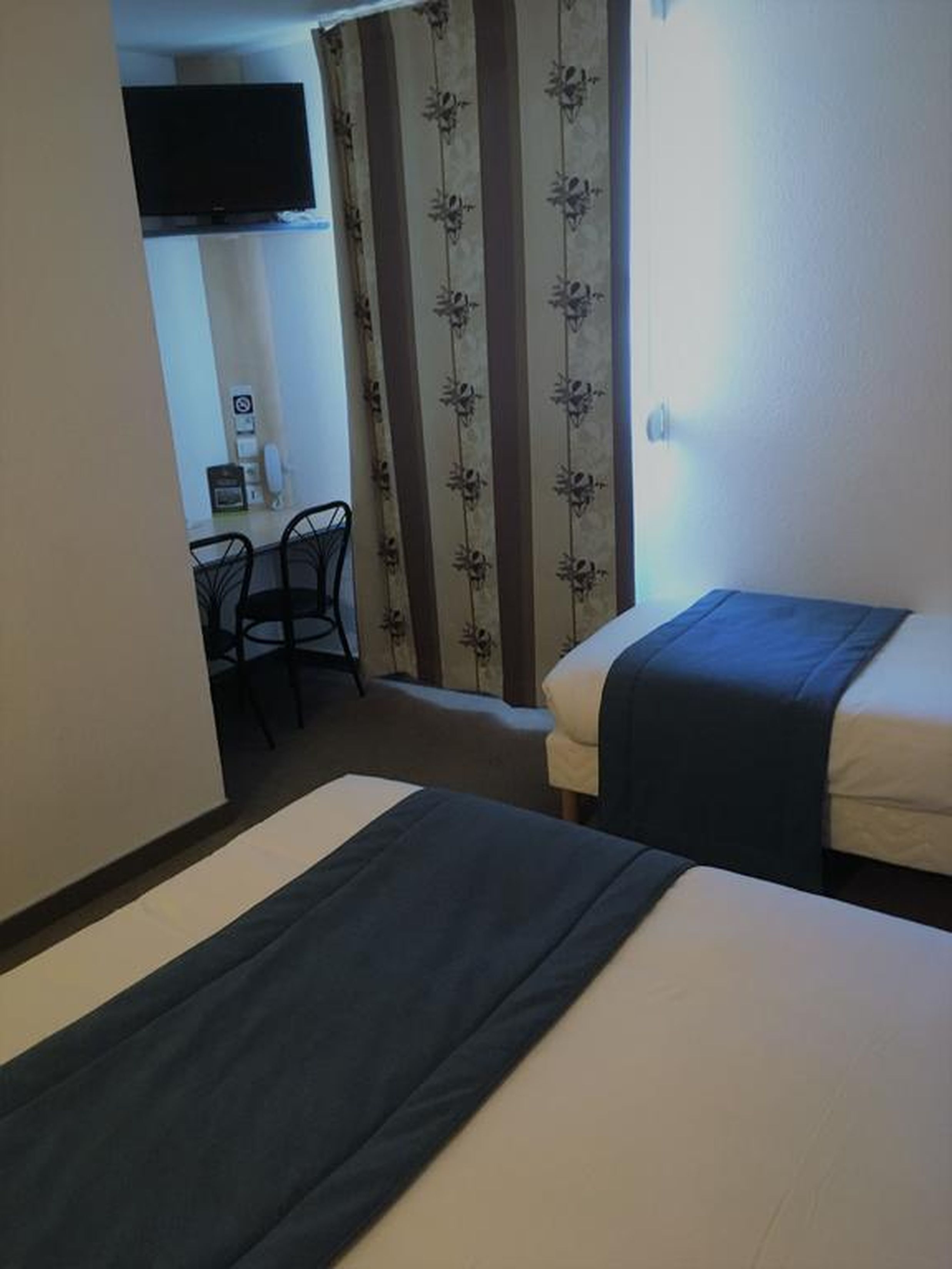 Une chambre d’hôtel avec deux lits, un bureau et une chaise.