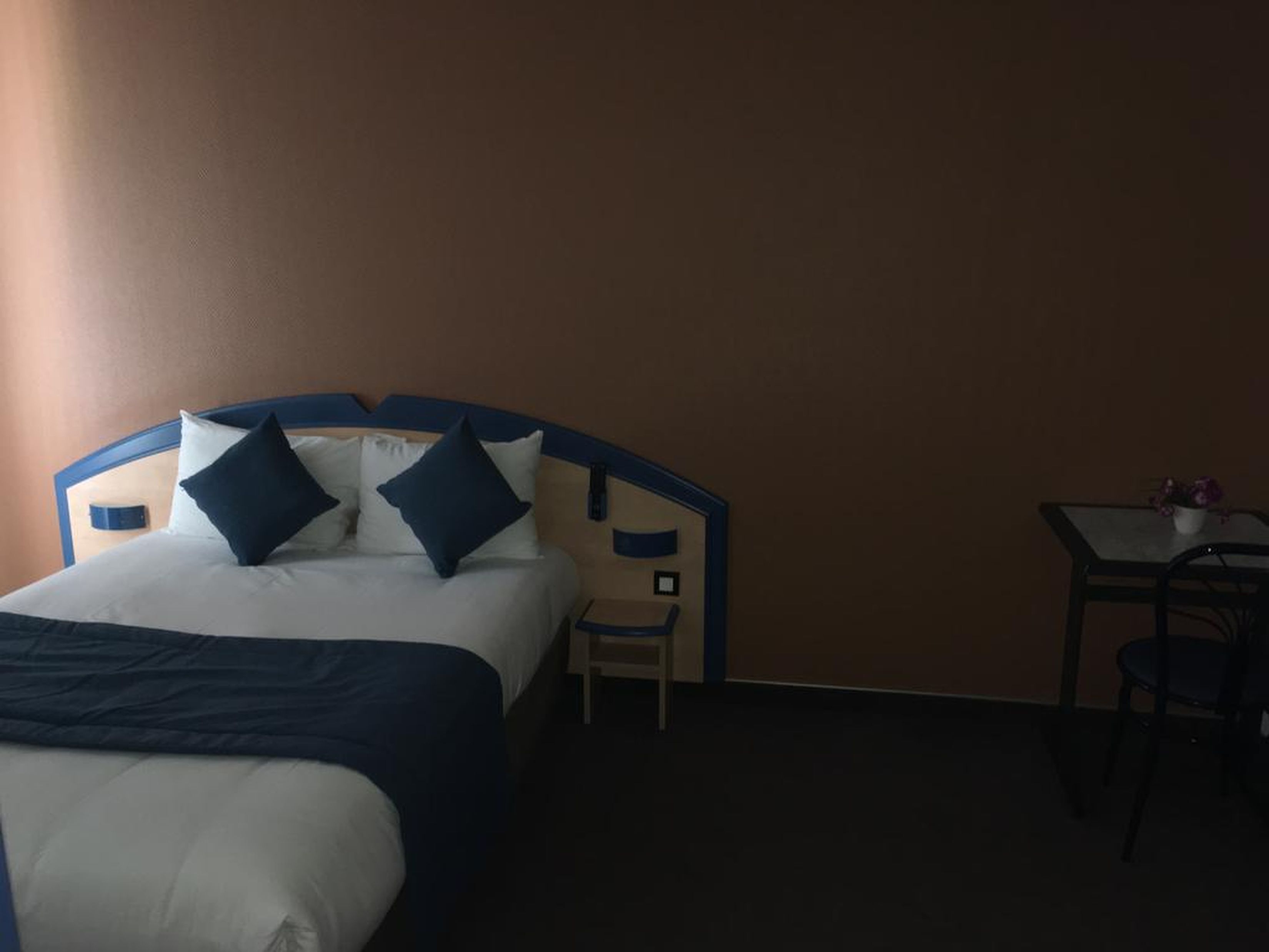 Una habitación de hotel con una cama, una mesita y una silla.