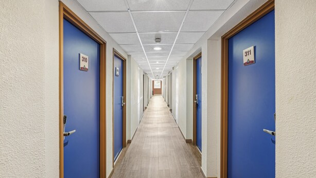 A hotel hallway with blue doors, numbered 310 and 311, and a light-colored wooden floor. - Hôtel Akena City Châteaurenard (Chateaurenard)