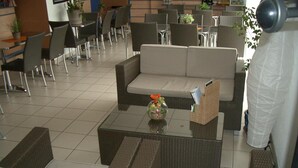A modern lounge area with wicker furniture, a glass coffee table, and a small plant. - Hôtel Akena City Châteaurenard (Chateaurenard)