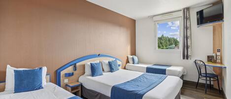 A hotel room with three beds, a desk, and a TV.