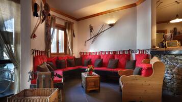 A cozy living room with a red sofa, wooden furniture, and a stone wall.