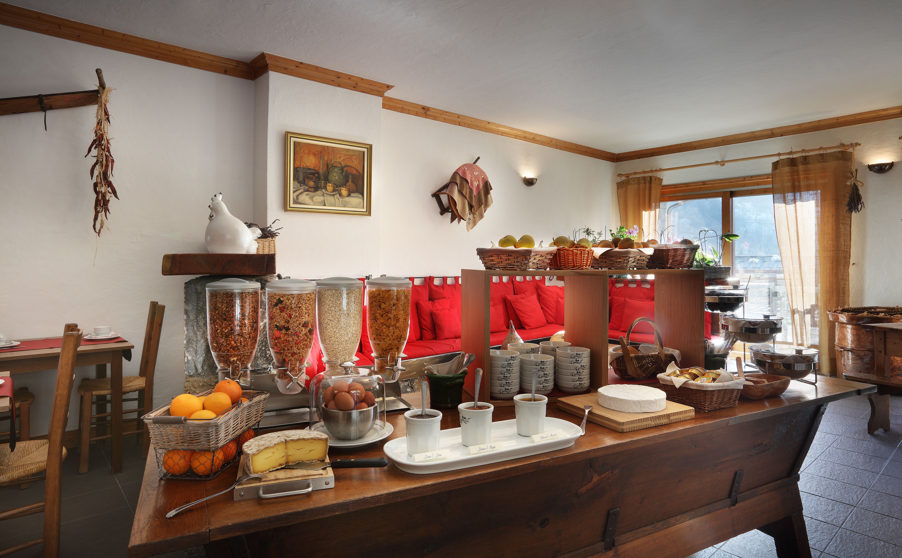 Una barra de desayuno con diversos alimentos, un sofá rojo y una ventana con vistas.