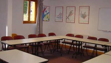 A conference room with tables and chairs, a whiteboard, and framed artwork on the wall.