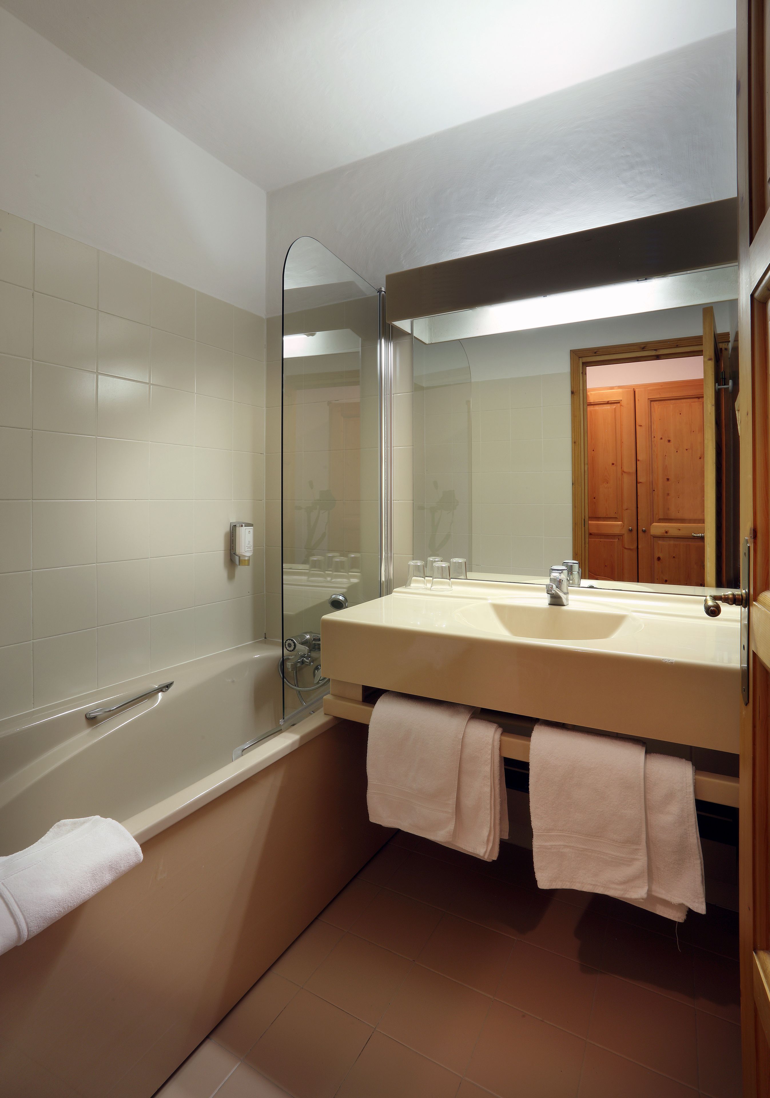 A bathroom with a bathtub, a sink, a mirror, and a door.
