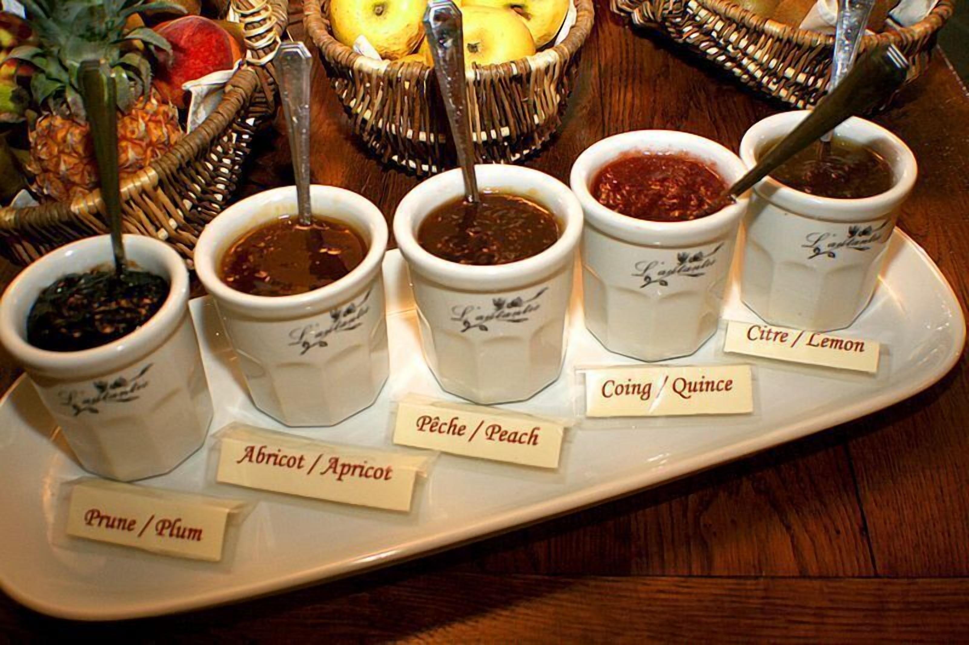 A tray with five small cups of jam, each labeled with a different fruit name.