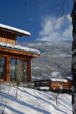 A wooden cabin with a snow-covered roof, stone foundation, and large windows. - Hôtel l'Autantic (Bourg-Saint-Maurice)