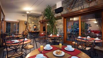 Een gezellig restaurant met stenen muren, houten tafels en stoelen.